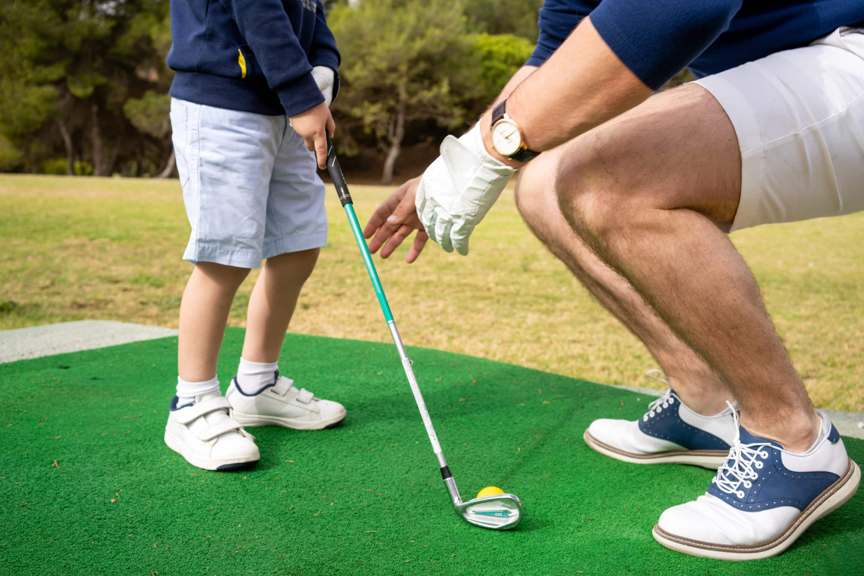 Father teaching his little son how to play golf
